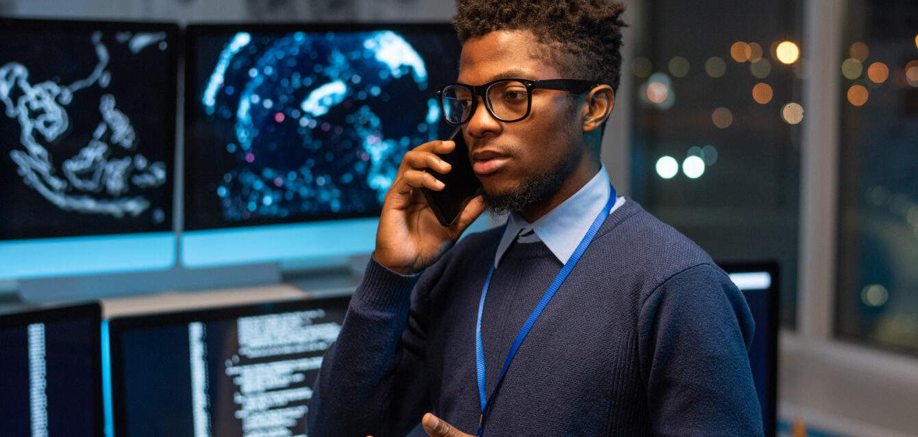 Young serious software developer or it-engineer consulting client on mobile phone